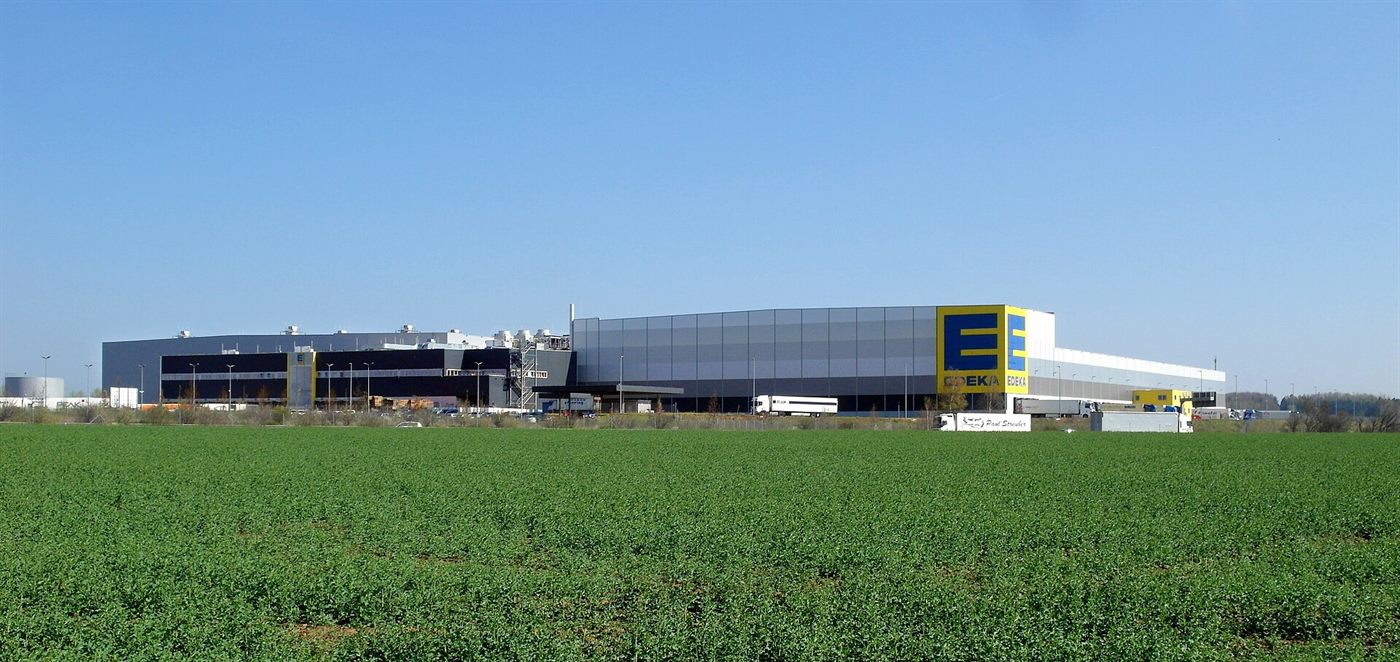 Prime logistics park with automated docks, solar roof and freight vehicles at dusk